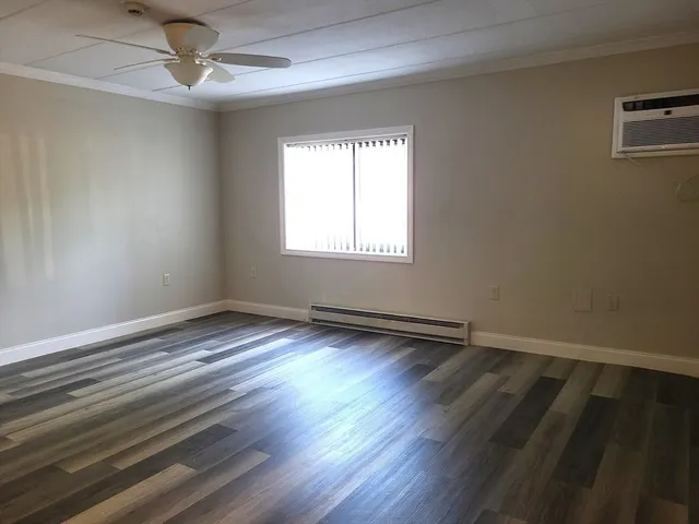 an empty room with wooden floor windows and fan