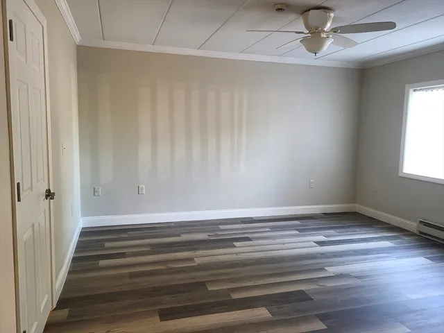 an empty room with wooden floor fan and windows
