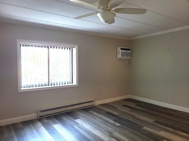 an empty room with wooden floor fan and windows