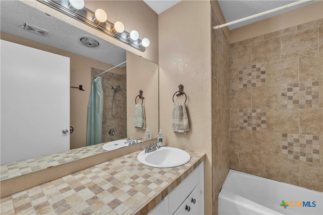 806 County Road 4756 Kempner, TX 76539 - Photo 17 of 33 a bathroom with a granite countertop sink a mirror and a bathtub