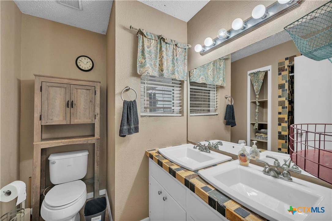 806 County Road 4756 Kempner, TX 76539 - Photo 20 of 33 a bathroom with a granite countertop sink vanity mirror and toilet