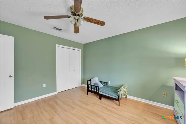 an empty room with a chandelier fan and windows