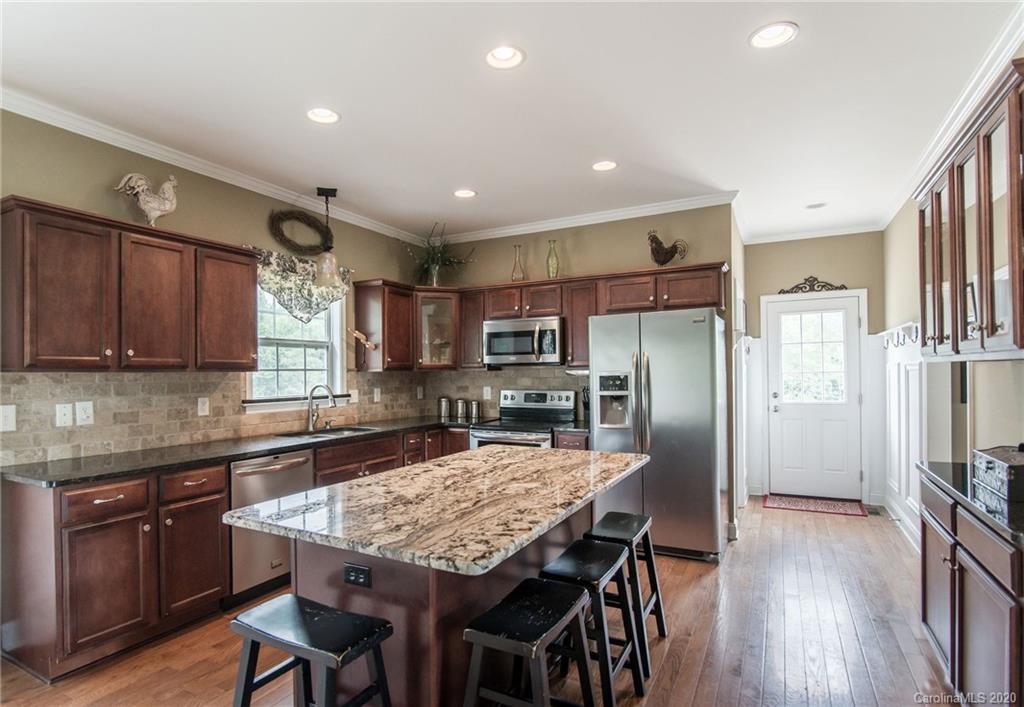 725 Hawley Road McConnells, SC 29726 - Photo 5 of 32 a kitchen with stainless steel appliances granite countertop a table chairs refrigerator and microwave