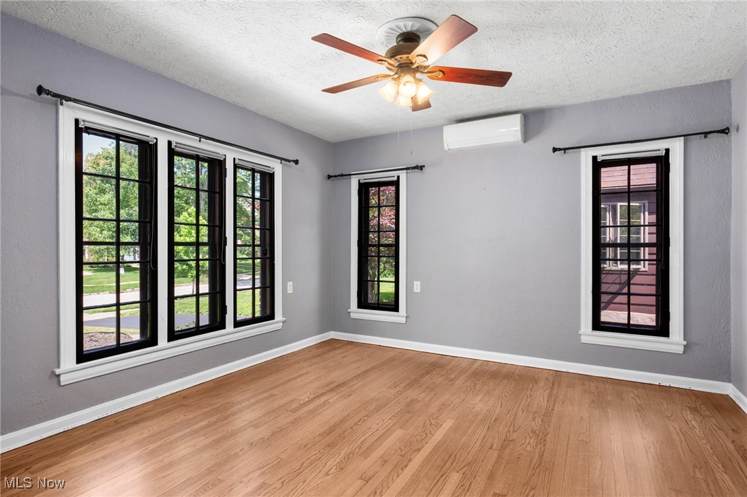 3677 Traver Road Shaker Heights, OH 44122 - Photo 9 of 35 Unfurnished room with a wall mounted air conditioner, baseboards, wood finished floors, a textured ceiling, and a ceiling fan