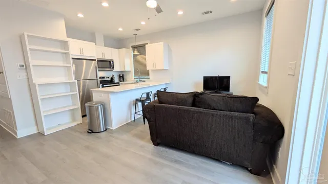 a living room with stainless steel appliances furniture and a view of kitchen