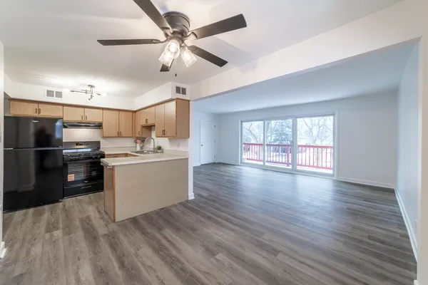a kitchen with stainless steel appliances kitchen island hardwood floor sink stove and wooden cabinets