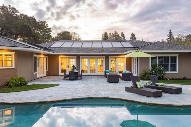 a view of a house with backyard sitting area and swimming pool