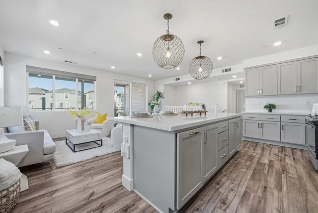 a large white kitchen with lots of counter space wooden floor and stainless steel appliances