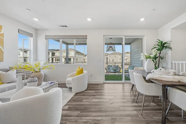 a living room with furniture a large window and wooden floor
