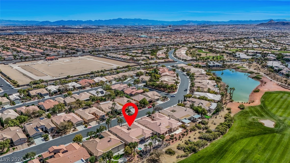 5015 Rivedro Street Las Vegas, NV 89135 - Photo 75 of 91 An aerial panorama reveals a vast residential community nestled alongside a golf course, complete with a serene lake.