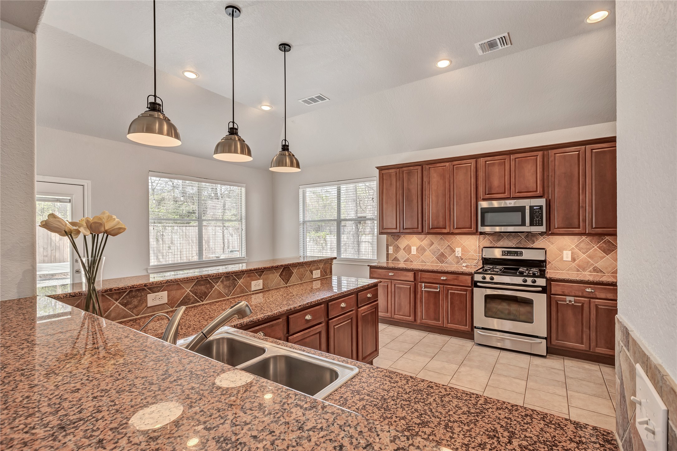 27 Planchard Court Spring, TX 77382 - Photo 3 of 16 a kitchen with stainless steel appliances granite countertop a stove a sink a oven with a dining table and chairs