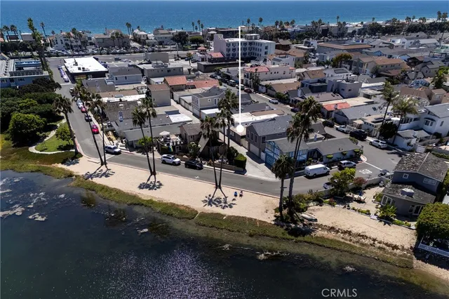 an aerial view of a city with lots of residential buildings and ocean view in back