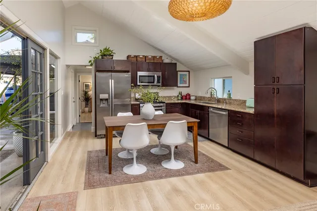 a kitchen with stainless steel appliances granite countertop a refrigerator a sink dishwasher a dining table and chairs with wooden floor