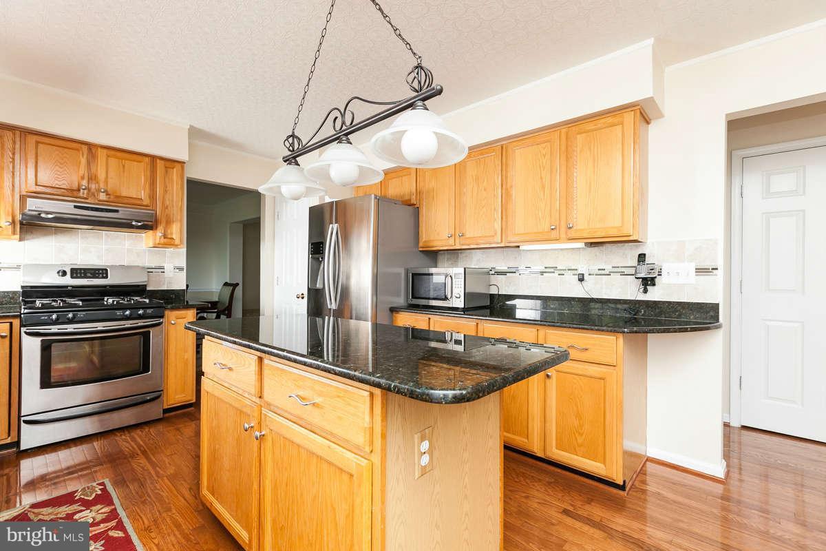 8596 Trail View Drive Ellicott City, MD 21043 - Photo 7 of 29 a kitchen with stainless steel appliances granite countertop a sink a stove and refrigerator
