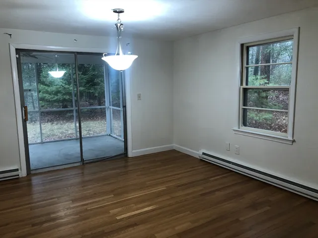a view of a room with wooden floor fireplace and windows