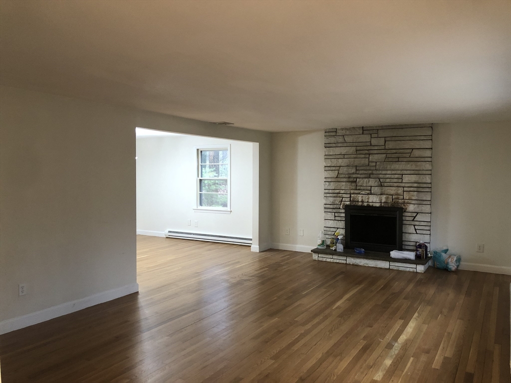 53 Deerhaven Road, Unit 1 Lincoln, MA 01773 - Photo 7 of 42 an empty room with wooden floor and fireplace