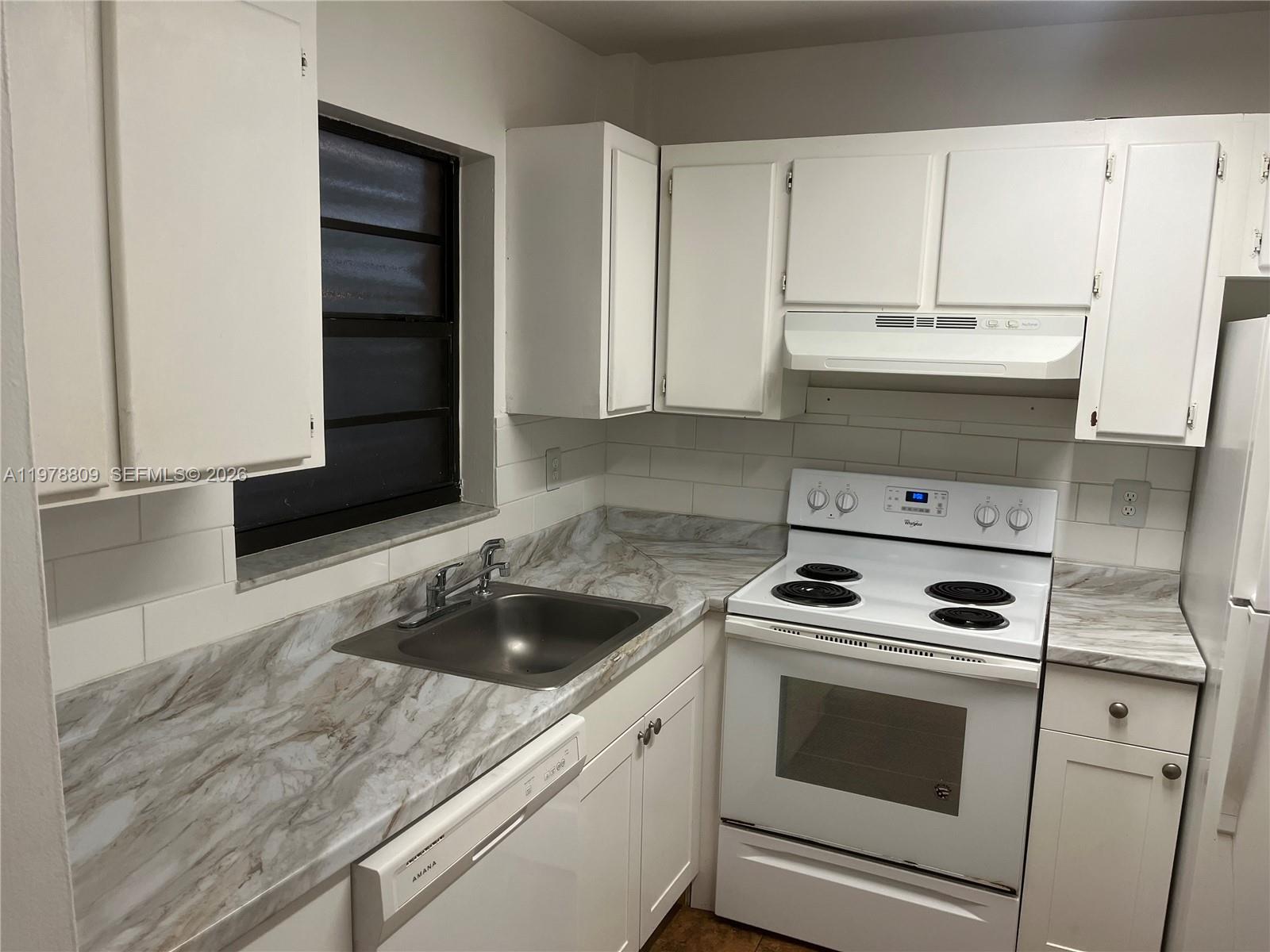 1250 Lincoln Road, Unit 310 Miami Beach, FL 33139 - Photo 11 of 27 a kitchen with granite countertop white cabinets and white appliances