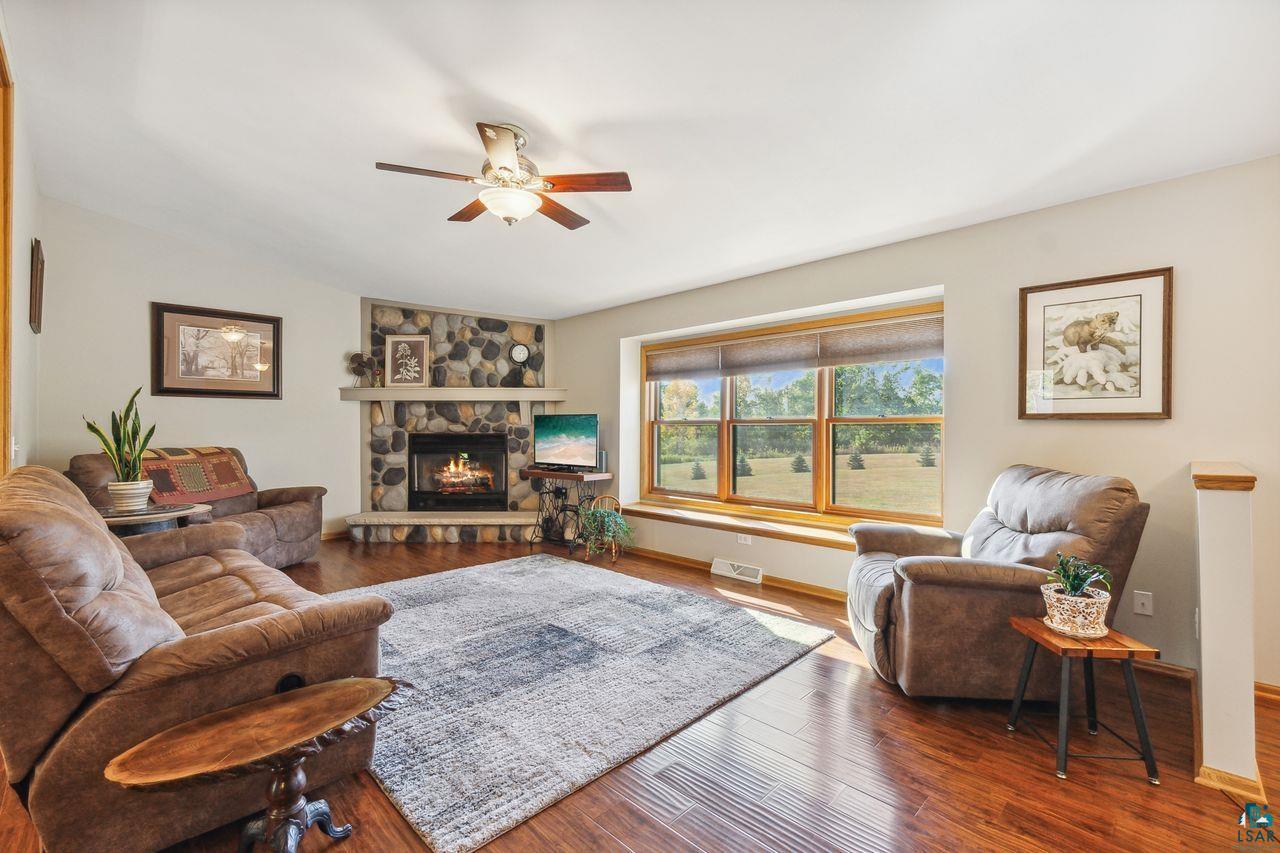 74050 Bjork Road Washburn, WI 54891 - Photo 3 of 33 Living room with ceiling fan, a stone fireplace, and hardwood / wood-style flooring
