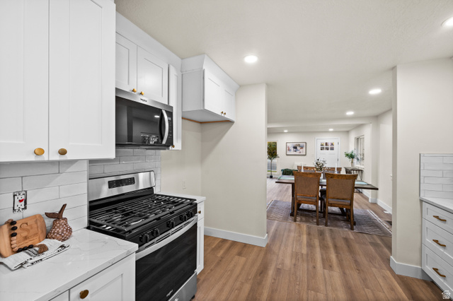 189 West Center Street Midvale, UT 84047 - Photo 15 of 64 Kitchen featuring white shaker cabinetry, stainless steel range and microwave, light subway tile backsplash, and wood-finish flooring
