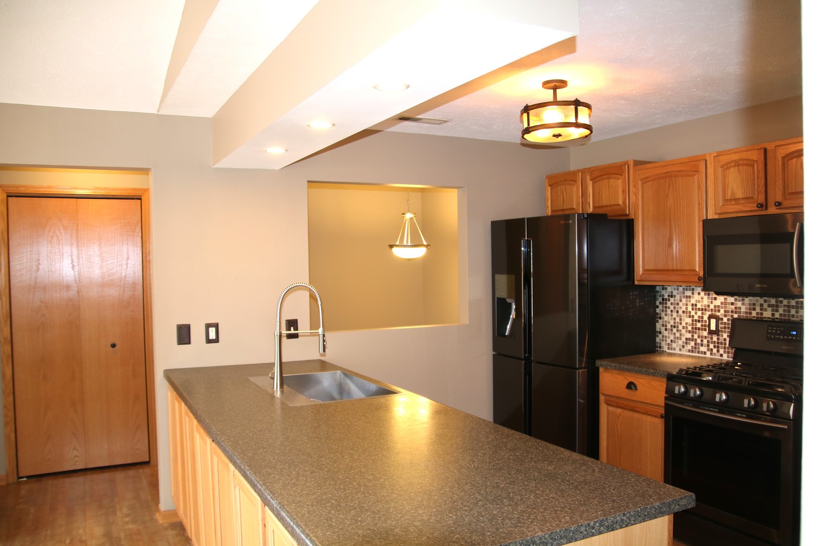 957 Arvle Circle, Unit 957 Sycamore, IL 60178 - Photo 6 of 17 a kitchen with stainless steel appliances granite countertop a refrigerator a stove and a sink with wooden floor