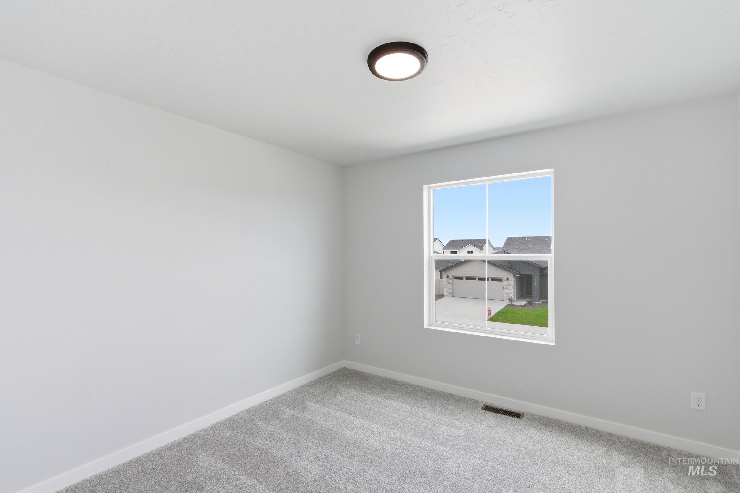 12829 Decatur Street Nampa, ID 83651 - Photo 20 of 33 Bright interior room featuring a single window, light gray walls, and gray carpet flooring