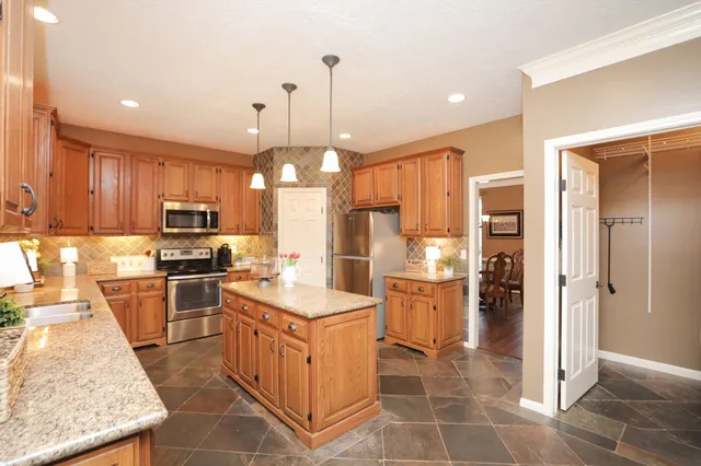 a kitchen with granite countertop a refrigerator oven a sink a stove and island