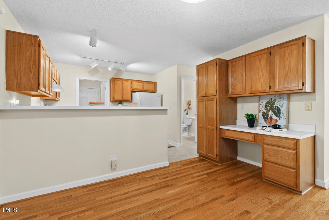3100 Wilderness Road Durham, NC 27712 - Photo 14 of 35 a kitchen with granite countertop wooden floors and white cabinets