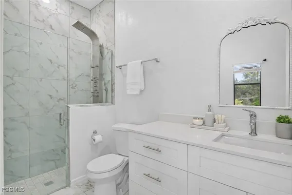 a bathroom with a granite countertop sink a toilet and a mirror