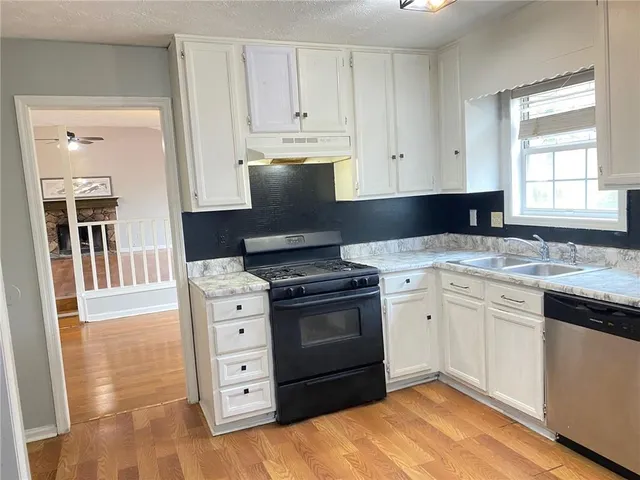 a kitchen with granite countertop a stove a sink and a microwave