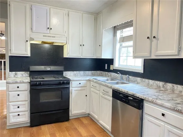 a kitchen with granite countertop a sink stainless steel appliances and cabinets