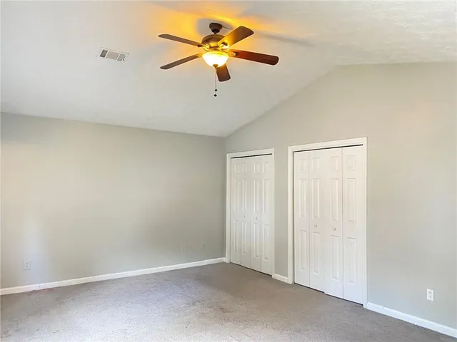 an empty room with closet and a ceiling fan