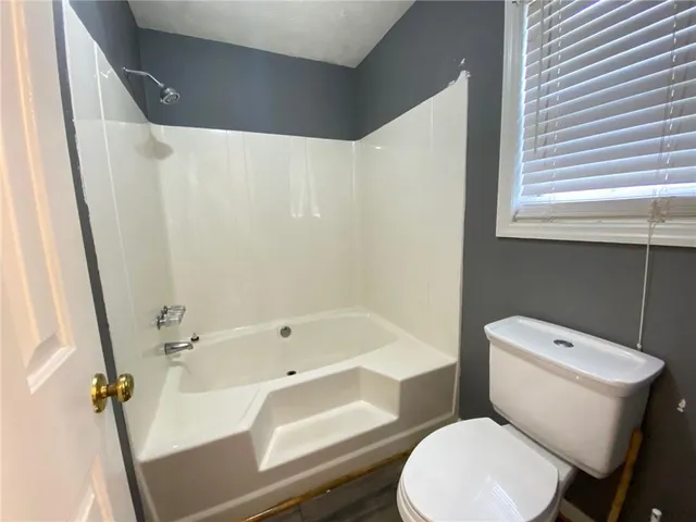 a white toilet sitting next to a bath tub