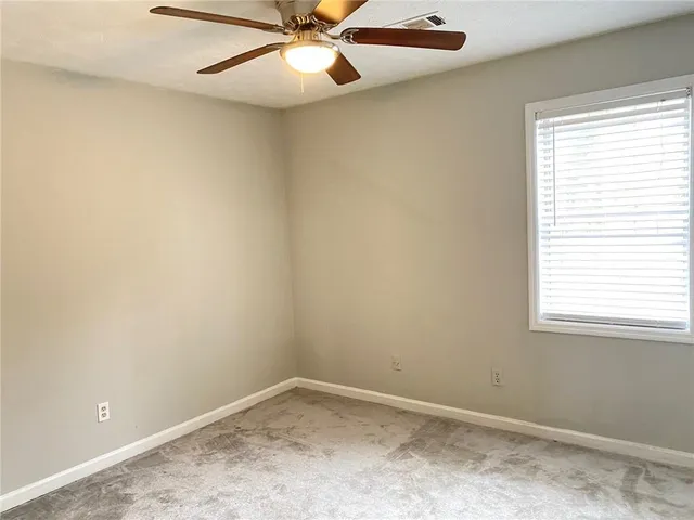 an empty room with a window and a fan