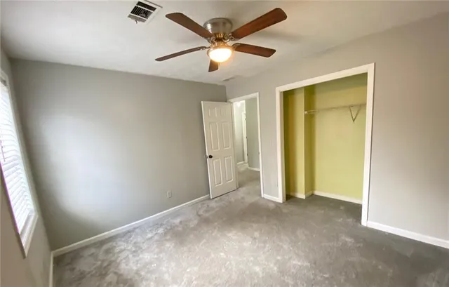 an empty room with closet and a ceiling fan