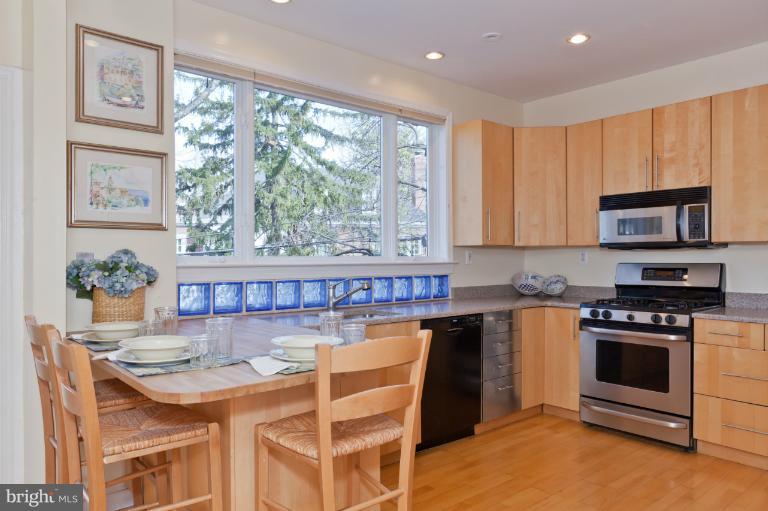 3219 Klingle Road Northwest Washington, DC 20008 - Photo 15 of 30 a kitchen with stainless steel appliances granite countertop a stove a refrigerator a microwave oven with a dining table and chairs