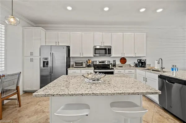 a kitchen with stainless steel appliances granite countertop a sink a microwave a refrigerator and cabinets