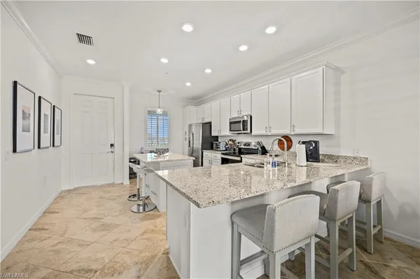 a kitchen with stainless steel appliances granite countertop a table chairs sink refrigerator and cabinets