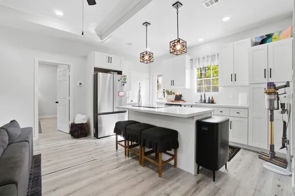 a kitchen with a refrigerator a sink dishwasher a dining table and chairs with wooden floor