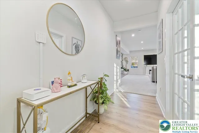 a hallway with a dining table a chandelier a mirror and a table