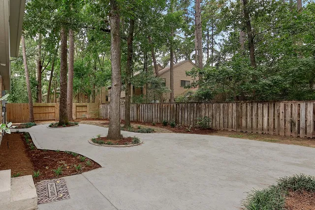a table and chairs sitting in a backyard with large trees