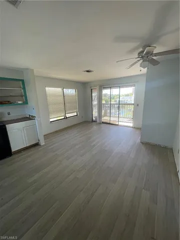 a view of an empty room with a window and wooden floor