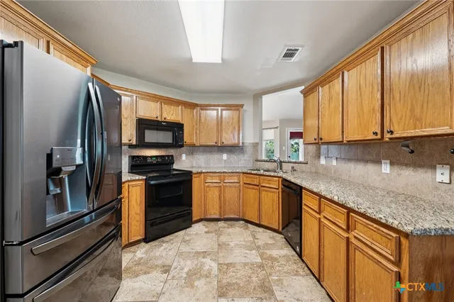 a kitchen with stainless steel appliances granite countertop a refrigerator a stove top oven a sink and dishwasher
