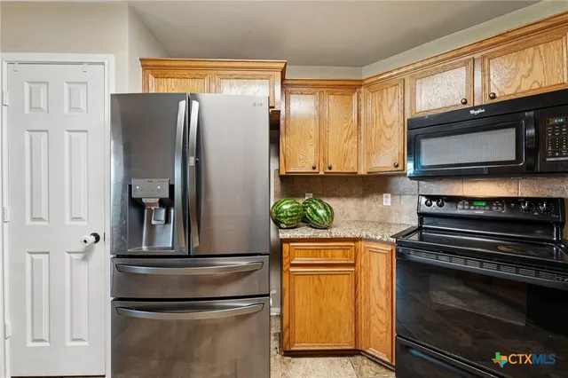 a kitchen with stainless steel appliances granite countertop a refrigerator and a stove top oven