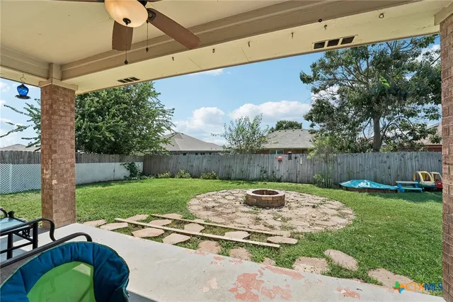 a view of a backyard with table and chairs potted plants and large tree
