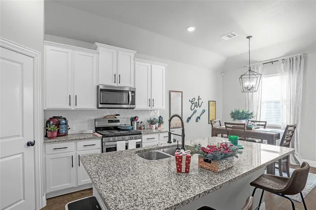 a kitchen with a refrigerator a stove and white cabinets