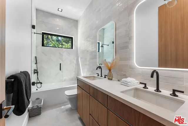 a bathroom with a double vanity sink toilet and a mirror