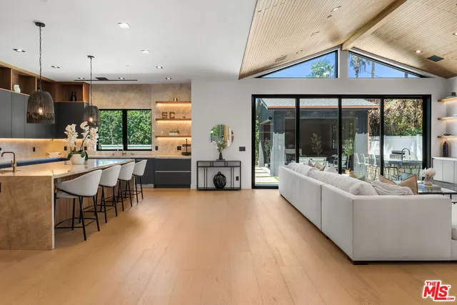 a living room with furniture a large window with kitchen view