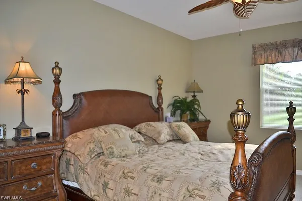 a bedroom with a bed and potted plant on the dresser