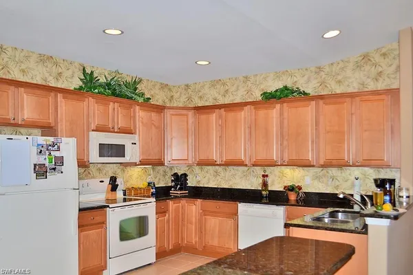 a kitchen with kitchen island granite countertop a sink a counter top space appliances and cabinets