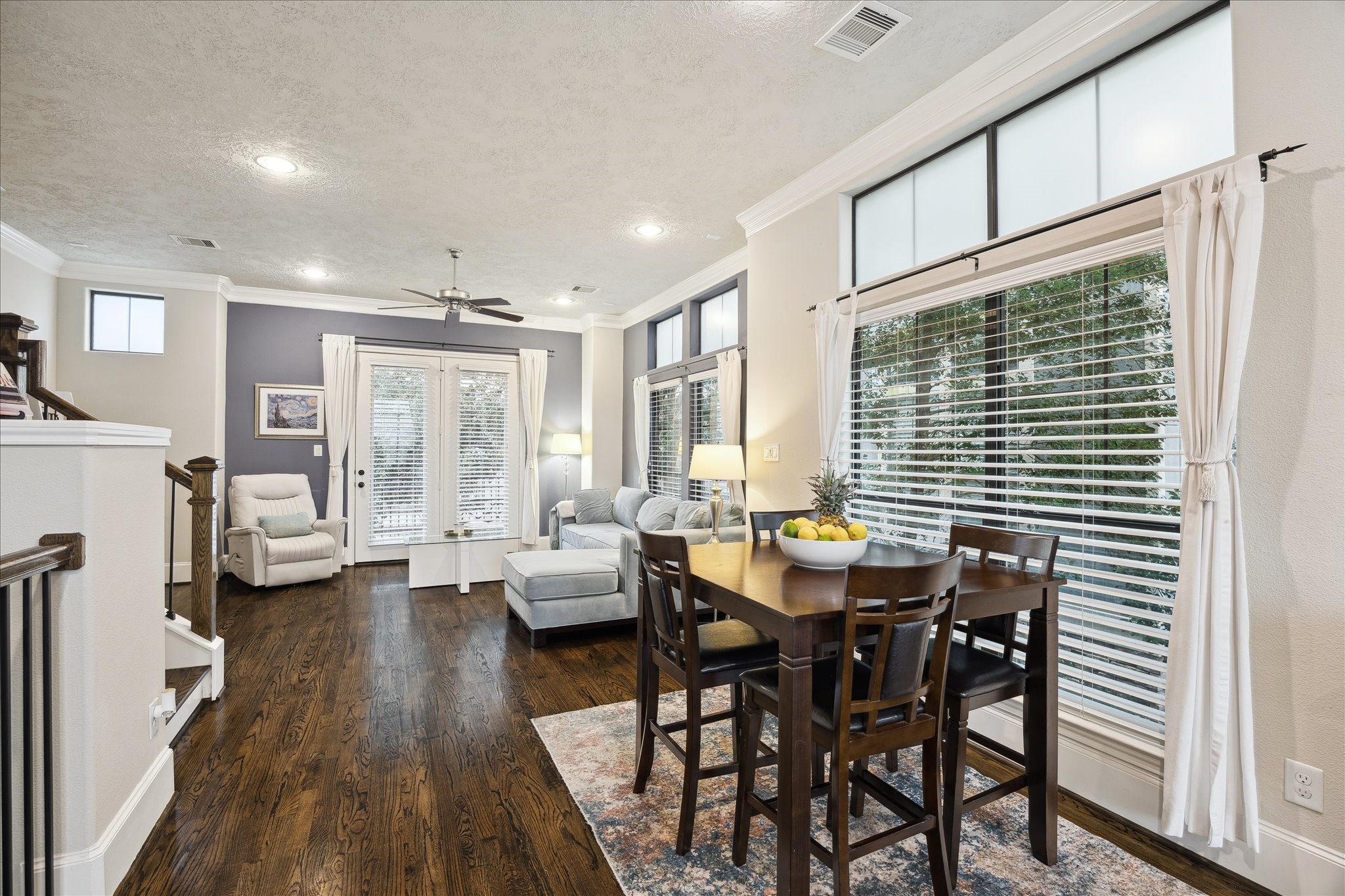 1110 West 25th Street Houston, TX 77008 - Photo 12 of 40 This bright and inviting dining area is perfectly positioned to take advantage of the home’s open layout and abundant natural light. Framed by oversized windows and soft, flowing curtains, the space feels airy and welcoming—ideal for everyday meals or hosting memorable gatherings. Warm hardwood floors and crown molding add timeless elegance, while the seamless connection to the living room creates an effortless flow for entertaining.